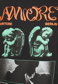 Black t-shirt featuring green angelic sculptures and orange text. Central image depicts a black and white silhouette of a couple kissing.