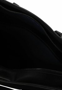 Schwarze Lederhandtasche mit offenem Reißverschluss, der das dunkle, leere Innenfutter und die Metallreißverschlusszähne entlang des Öffnungskanten der Tasche zeigt.