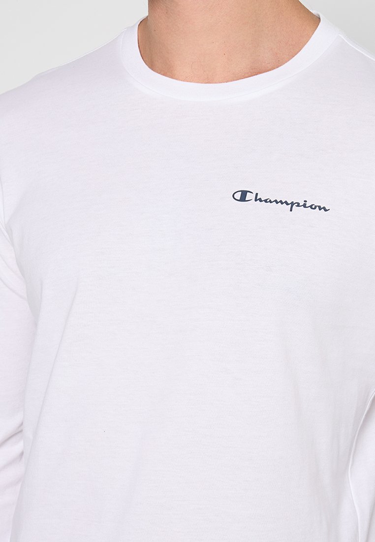 Camiseta de algodón de manga larga blanca con el logotipo de "Champion" en azul marino en el pecho. Tejido suave y cuello redondo. Diseño sencillo.