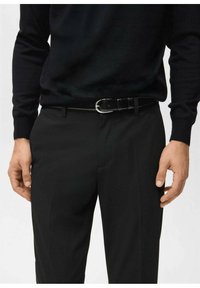 Czarny skórzany pasek ze srebrną klamrą, noszony na czarnych spodniach i czarnym dzianinowym swetrze, prezentujący elegancki i minimalistyczny design.