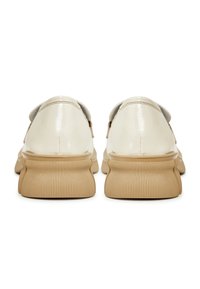 Paire de chaussures en cuir verni beige avec semelles épaisses côtelées brun clair, vues de dos sur fond blanc.