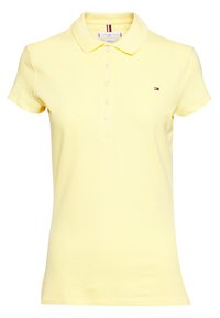 Vaaleankeltainen naisten lyhythihainen polo-paita, jossa on kaulus, viisi nappia ja pieni Tommy Hilfiger -logo rinnassa.