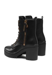 Stivali alla caviglia in pelle nera con tacco alto e spesso, hardware in tono oro, lacci frontali e zip laterale con un tirante a marchio.