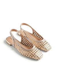 Bailarinas beige de tejido trenzado con diseño de celosía abierta, punta cerrada y tacón bajo, mostradas lado a lado sobre fondo blanco.