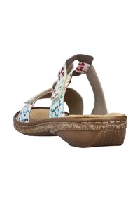 Sandale blanche avec des motifs bleus, rouges et verts, dotée d'une sangle arrière et d'une fermeture Velcro ajustable. Semelle texturée marron.
