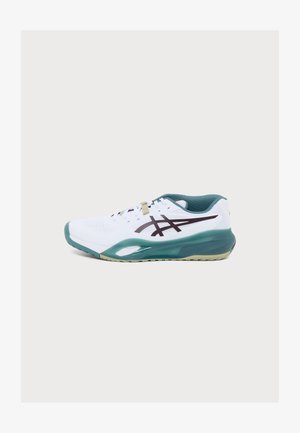 Chaussure de sport blanche avec semelle et intérieur verts, présentant des bandes logo noires sur le côté, affichée sur un fond clair uni.