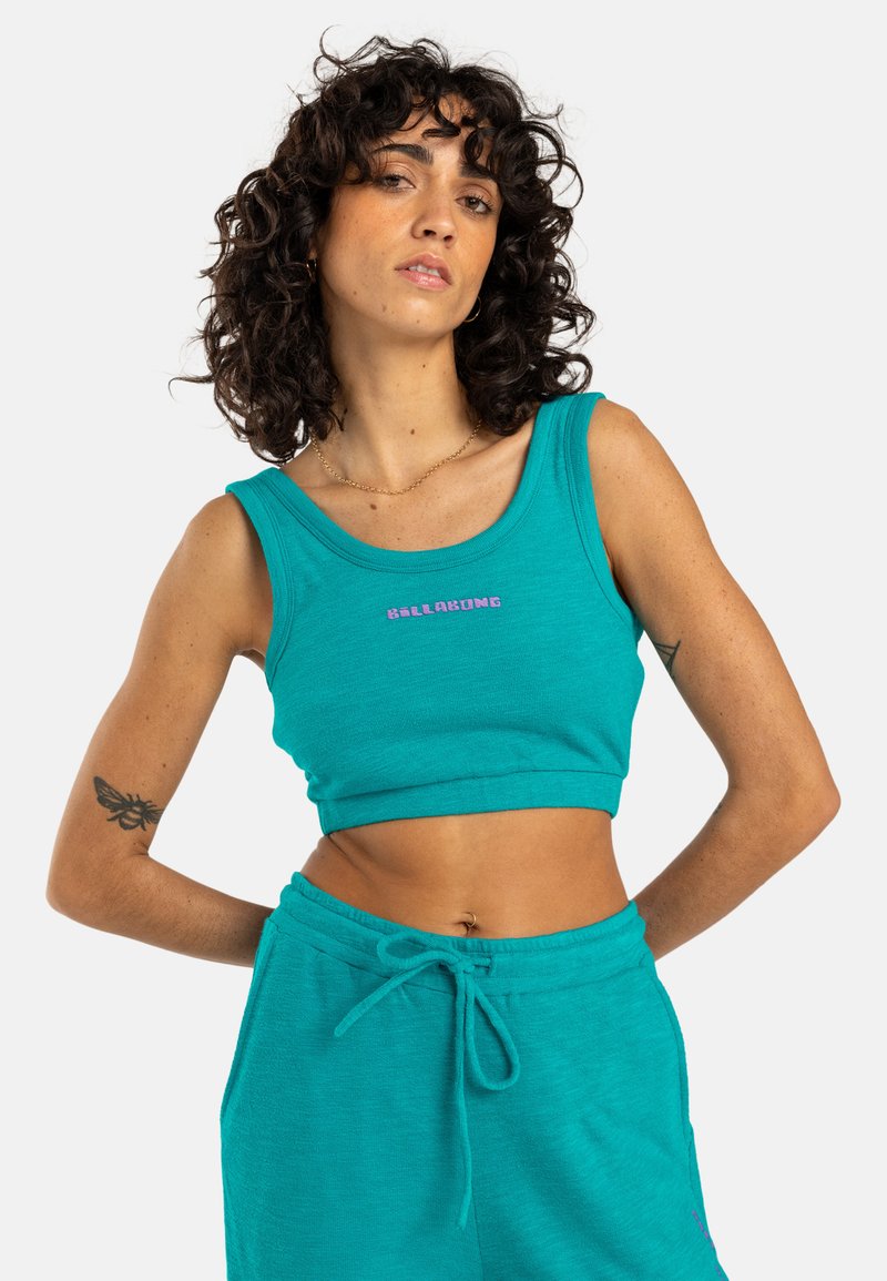 Turquoise crop top van zacht materiaal, met een ronde halslijn en een "BELLABONG" logo in contrasterend paars. Eenvoudige snit zonder versieringen.