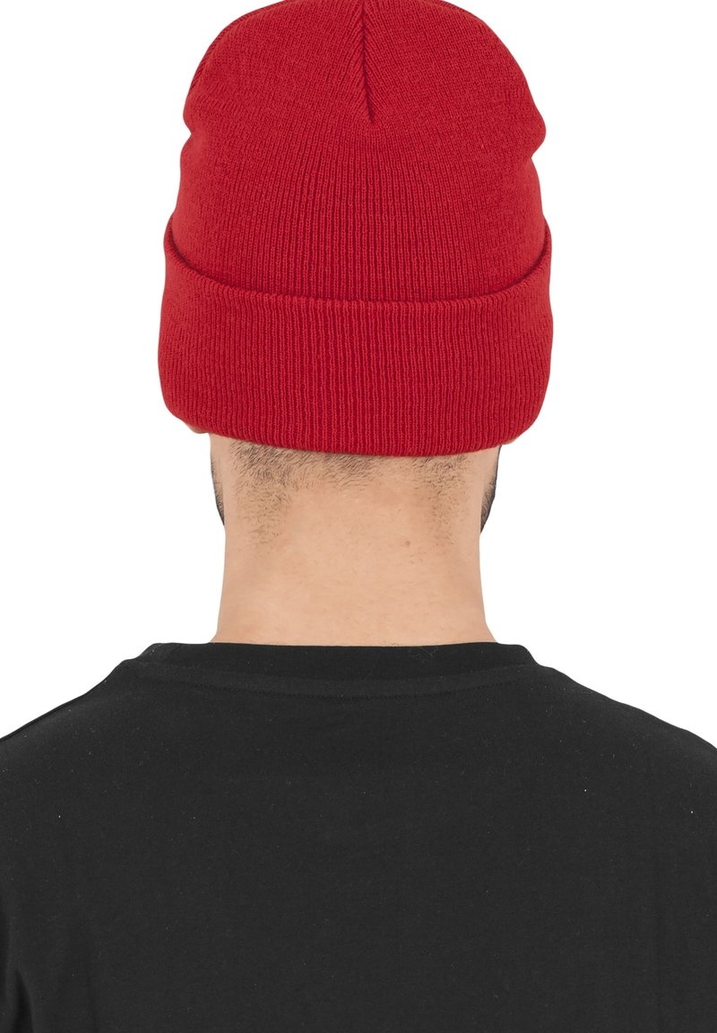 Personne de dos portant un bonnet tricoté rouge vif et un t-shirt noir uni.
