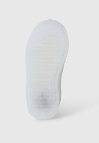 Suola di sneaker bianca con una superficie liscia, caratterizzata da un motivo a nido d'ape e bordi arrotondati. Il materiale appare gommato e flessibile.
