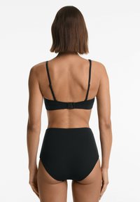 Fekete bikini szett, amely egyszerű bralette-ből áll, állítható pántokkal és magas derekú alsókkal, matt textúrával és minimális hardverrel.