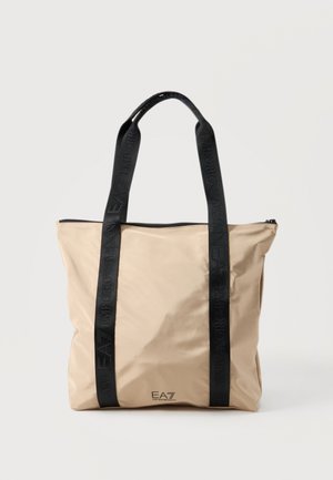 Sac fourre-tout beige avec de longues poignées noires comportant un logo embossé EA7 Emporio Armani, et une fermeture éclair en haut.