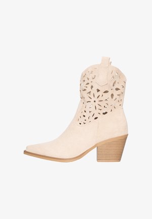 Beiger Wildleder-Stiefelette mit spitzer Zehenpartie, floralem Cut-out-Muster am Schaft, Zuglasche, gestapeltem Blockabsatz und hellbrauner Sohle.