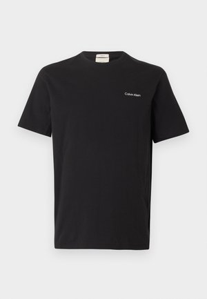 T-shirt décontractée noire à manches courtes avec col rond et petit logo blanc "Calvin Klein" sur la poitrine gauche.