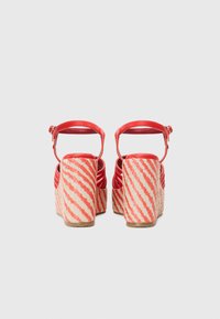 Røde lærplattform sandaler med en vevd, stripete jute hæl. Har ankelstropp og åpen bakdesign for enkel påkledning.