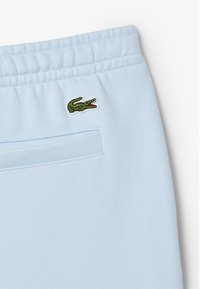 Felpa azzurra con vita a coste, dotata di un piccolo logo ricamato di un coccodrillo verde sul lato sinistro e una tasca posteriore.