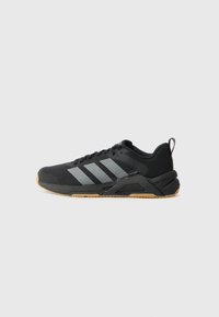 Black athletic shoe with gray stripes, a textured upper, and a rubber sole. Features a reinforced heel and a pull tab for easy wear.