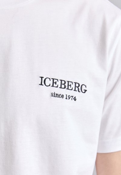 T-shirt en coton blanc avec le texte brodé en noir "ICEBERG depuis 1974" situé sur la partie gauche de la poitrine. Manches courtes et design à col rond.