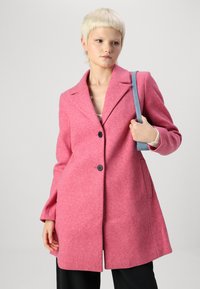Roze wollen blend jas met een reverskraag, sluiting met twee knopen en zijzakken. Voorzien van lange mouwen en een getailleerde pasvorm.