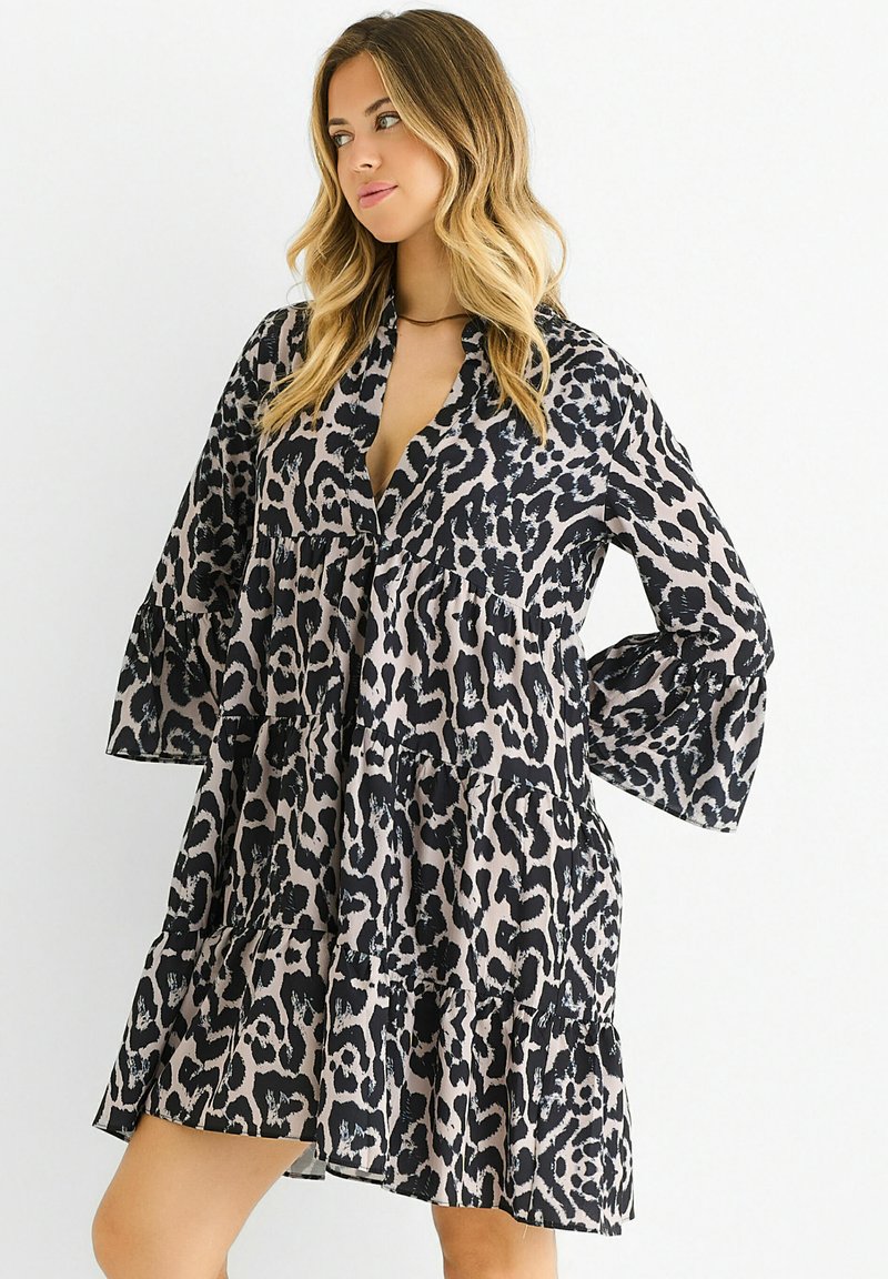 Leopard print dress in light beige and black, featuring a V-neck, tiered ruffles, and bell sleeves. Made from lightweight fabric.