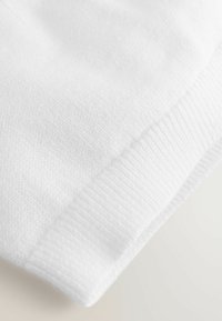 Tissu blanc avec un tissage texturé et des bords côtelés. La vue en gros plan met en évidence la douceur et la douceur du matériau.