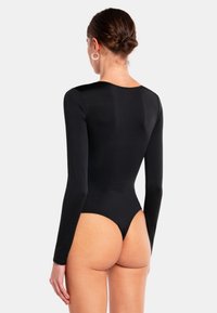 Body a maniche lunghe nera, realizzato in tessuto liscio ed elastico. Presenta una gamba alta e un collo rotondo, offrendo una silhouette attillata.