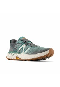 Zapatilla de running para hombre con parte superior de punto transpirable en tonos azul verdoso y gris, acentos blancos, suela de goma marrón resistente y marca Vibram.