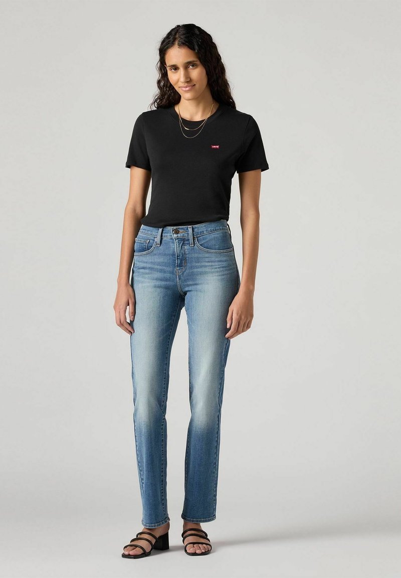 Czarna bawełniana koszulka z czerwoną grafiką, połączona z jasnoniebieskimi dżinsami o wysokim stanie i delikatnym wyblaknięciu oraz czarnymi sandałami na paski.