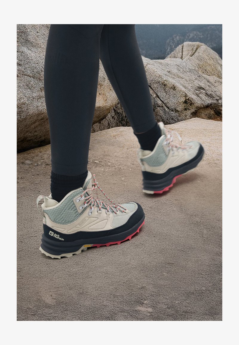 Chaussures de randonnée légères avec une tige beige, en matériaux mesh et cuir, accents gris, semelle en caoutchouc rose et noir, et lacets à motif.