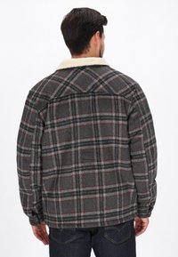 Grå ternet flanneljakke med en skindkrave. Har sorte og røde linjer, lange ærmer og knapmanchetter. Bagview.