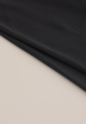 Tessuto nero con una consistenza liscia, piegato ordinatamente su una superficie beige. Il tessuto appare leggero e flessibile.