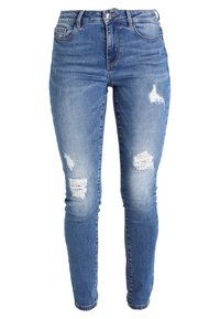 Siniset farkut, jotka ovat kapeat ja joissa on kulutettuja yksityiskohtia, kuten revittyjä paikkoja etuosassa. Klassinen viiden taskun malli ja nappikiinnitys.