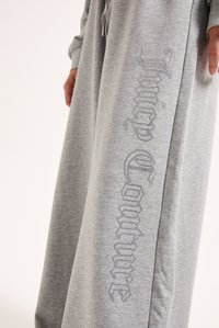 Pelēkie sporta bikses no mīksta auduma, ar samta dekorācijām, kas izveido vārdu "Juicy Couture" sānos. Brīva piegriezuma un elastīgs jostasvieds.