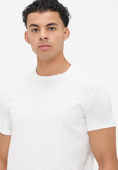 Weißes T-Shirt mit kurzen Ärmeln, das ein sich wiederholendes Logo-Muster in Ton-in-Ton mit "DSQUARED2" zeigt. Slim Fit mit Rundhalsausschnitt und weichem Stoff.