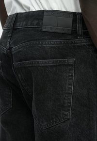 Μαύρο τζιν από ντένιμ με υφή υφάσματος, σχεδιασμό με ίσια γραμμή, πίσω τσέπες και ματ μαύρο δερμάτινο λογότυπο στη μέση.