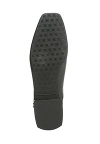 Suola in gomma nera con un motivo testurizzato che presenta un logo impresso. Il tacco è basso e quadrato, progettato per stabilità e comfort.