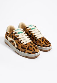 Sneakers kuvitettu leopardin kuvioilla beigen ja mustan sävyillä, kermanväriset nauhat ja harmaa yksityiskohta kantapäässä. Varustettu kumipohjalla pidon parantamiseksi.