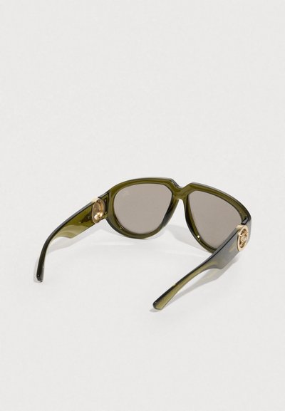Γυαλιά ηλίου σε ελιά πράσινο με στρογγυλεμένους φακούς, που διαθέτουν χρυσές μεταλλικές λεπτομέρειες στα βραχίονες, κατασκευασμένα από γυαλιστερό πλαστικό υλικό.
