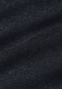 Close-up van donkerblauwe stof die de gedetailleerde gebreide textuur en fijne vezels in zachte plooien toont.
