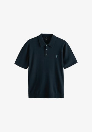 Tumesinine lühikeste varrukatega polo särk, mis on valmistatud kudumkangast, omades klassikalist kaelaosa ja kolme nupuga plakeed väikese tikklogooga.