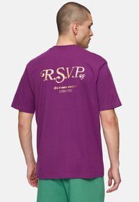 Lilla bomulds T-shirt med guldtekst "R.S.V.P." og "fila tennis society" på ryggen; korte ærmer og en afslappet pasform.