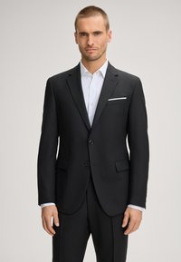 Schwarzer, maßgeschneiderter Anzugsblazer mit zwei Knöpfen, Kerbkragen und Pattentaschen. Weißes, gemustertes Hemd schaut von den Manschetten und der Tasche hervor.