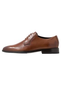 Chaussure habillée en cuir marron avec une finition lisse, un bout rond et cinq œillets pour les lacets. Présente un talon carré bas et un branding minimal.