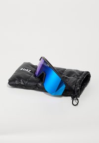 Sonnenbrille mit schwarzem Rahmen und verlaufenden blau-lila Gläsern, die auf einem schwarzen gepolsterten Etui mit Logo liegt. Winkeliges Design, reflektierende Oberfläche.