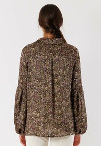Blusa con motivo floreale marrone, dotata di colletto, maniche lunghe a sbuffo e vestibilità ampia con orlo dritto. Tessuto strutturato.