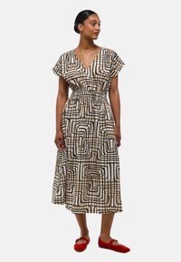 Robe midi à motifs avec un décolleté en V profond, des manches courtes et une taille élastique. Les couleurs incluent le blanc, le noir et le marron, avec un design géométrique.