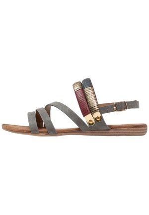 Sandale en daim gris avec trois brides accentuées de couleurs rouge, bleu et doré, dotée d'une semelle en bois plate et d'une fermeture à boucle ajustable à la cheville.