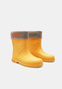 Botas de goma amarillas con un puño de fieltro gris, que presentan una suela texturizada, líneas de diseño curvas y una etiqueta de marca cosida en el puño.