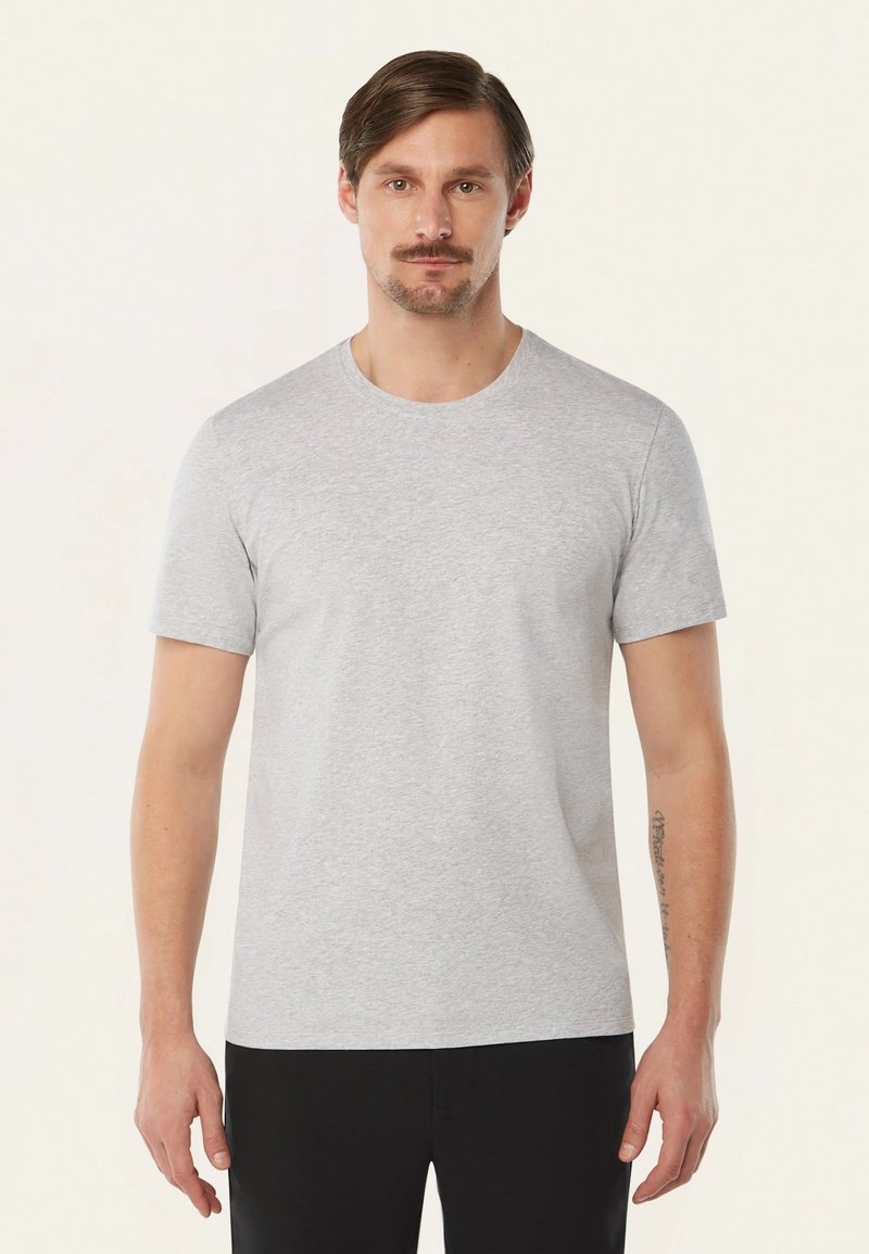 Grijze t-shirt met korte mouwen in een zachte katoenmix, voorzien van een ronde kraag en een minimalistisch ontwerp, gecombineerd met zwarte broeken.