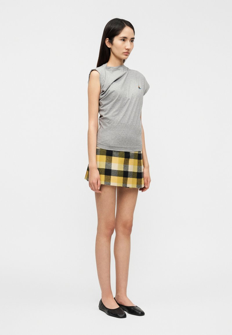 Gray fitted top with an asymmetric shoulder design, paired with a yellow and black plaid mini skirt. Black ballet flats complete the look.