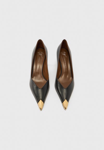 Scarpe con tacco alto in pelle nera con punte appuntite e dettagli dorati sulla punta. Interno marrone con texture liscia.